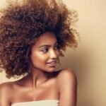 Beauty portrait of african american black woman with clean healthy skin on beige background. Skin care and cosmetic. Smiling beautiful afro girl.Curly hair